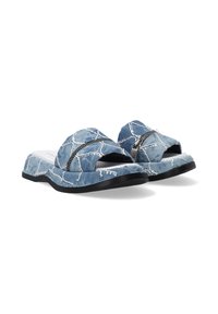Denim slide sandaler med krydsende remme, lyseblå farve, dekorativ hvid syning og en sort sål. Tekstureret indersål design.