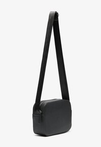 Sac bandoulière noir en matériau synthétique. Forme rectangulaire, fermeture éclair, et sangle texturée avec réglage. Fini lisse.