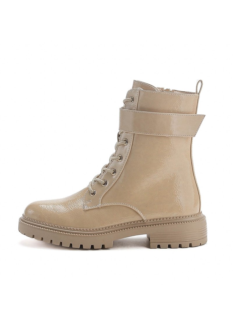 Bottes chelsea beiges en matériau brillant avec un bout rond, un laçage sur le devant, une sangle latérale et une semelle en caoutchouc texturée.