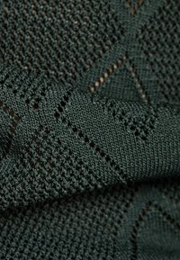 Tejido de punto en verde oscuro, con un patrón de diamantes y líneas texturizadas, que presenta una trama abierta y un acabado suave.