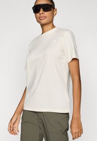 Κρεμ κοντομάνικο μπλουζάκι από μαλακό βαμβάκι με στρογγυλή λαιμόκοψη. Διαθέτει ένα μικρό λευκό λογότυπο στο αριστερό μέρος του στήθους. Φοριέται με παντελόνι σε ελιά χρώμα.