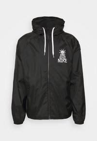 Černá nylonová bunda se zapínáním na zip, elastickými manžetami a kapucí. Na hrudi se nachází bílá logo a kontrastní šňůrky.