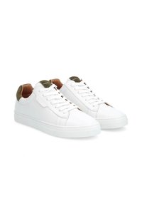 Weiße Sneakers mit einem glatten Lederobermaterial, passenden weißen Schnürsenkeln, grünen Wildleder-Akzenten an der Ferse und strukturierten Gummisohlen.