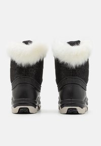 Para czarnych zimowych butów z białym futrzanym wykończeniem, widocznych z tyłu, z gumowymi podeszwami i ocieplonymi górnymi częściami.