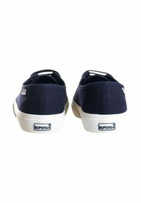 Sneakers in tela blu navy con suole in gomma bianca, caratterizzati da una suola testurizzata e un marchio sul tallone. Il design include accenti minimalisti.