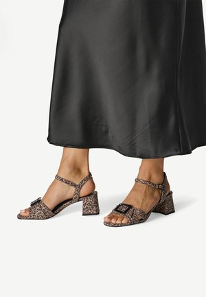 Blokhælede sandaler med leopardprint, åben tå, justerbar ankelrem og en dekorativ spændeaccentering. Tekstureret stof med en mat finish.