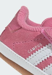 Růžové semišové tenisky s texturovaným svrškem, bílými koženými pruhy a gumovou podrážkou. Obsahují švy a štítek „CAMPUS“.}}