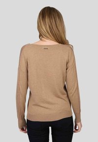 Pull en tricot beige avec un encolure large et des détails en points ouverts le long des manches. Sa texture lisse et ses poignets côtelés améliorent l'ajustement.