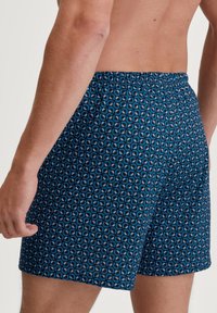 Heren zwembroek in het blauw met een geometrisch patroon. Heeft een elastische tailleband en een ontspannen pasvorm voor comfort en bewegingsvrijheid.