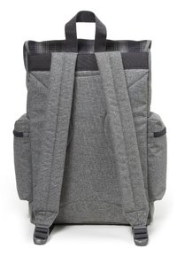 Grå tygryggsäck med vadderade axelremmar, två sidofickor och ett handtag på toppen. Texturerad yta med subtila sömnadsdetaljer.