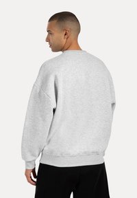 Grå sweatshirt med afslappet pasform, rund halsudskæring, sænkede skuldre og ribbede manchetter og kant. Blød tekstur, minimalistisk design, ingen synlige logoer.