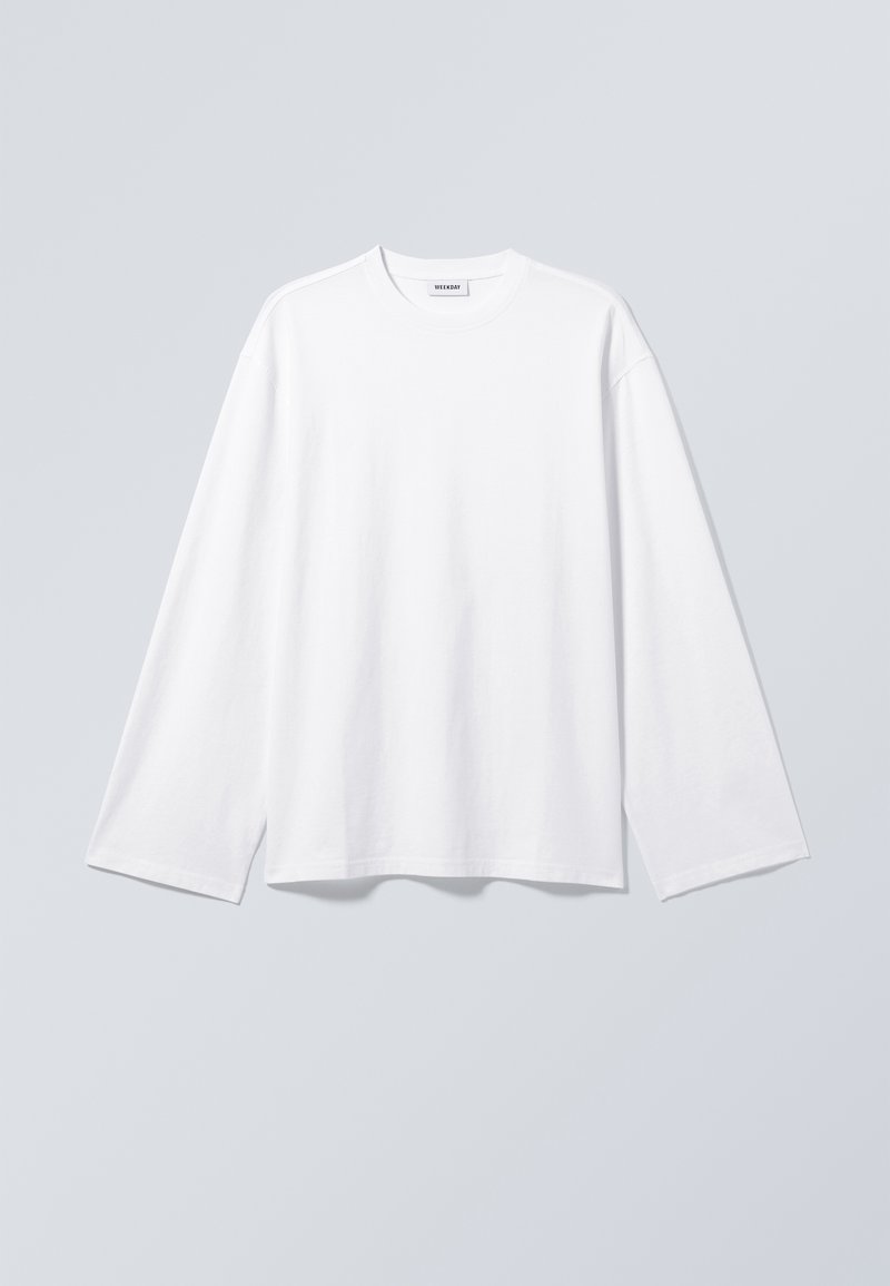 Κλασικό λευκό μακρυμάνικο μπλουζάκι με στρογγυλή λαιμόκοψη, απλωμένο επίπεδα πάνω σε ανοιχτό γκρι φόντο, με ορατή ετικέτα της μάρκας Weekday στην εσωτερική πλευρά του γιακά.