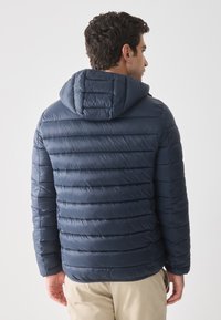 Námořnický modrý péřový kabát vyrobený z lehkého materiálu, s kapucí, prošívanou texturou, horizontálními švy a elastickými manžetami.