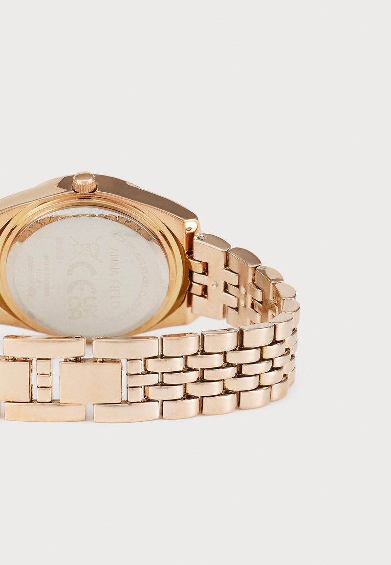 Montre-bracelet dorée dotée d'un boîtier rond, d'un fond en acier inoxydable et d'un bracelet métallique à maillons avec une texture lisse et une finition polie.