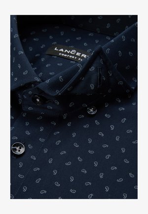 Granatowa koszula wykonana z gładkiego materiału, zdobiona białym wzorem paisley, z klasycznym kołnierzykiem i dwoma czarnymi guzikami z przodu.
