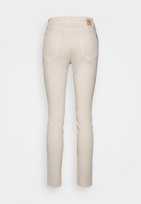 Jeans ajustados de color beige claro con una textura suave, dos bolsillos traseros y un parche de cuero de marca en la cinturilla.