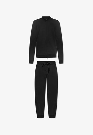 Czarny dres składający się z kurtki zapinanej na zamek z stójką oraz pasujących spodni. Posiada elastyczne mankiety i pasek ze ściągaczem.