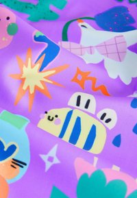 Farverigt stof med tegneserie-designs i forskellige former, sat på en lavendelfarvet baggrund. Bemærkelsesværdige accenter inkluderer en smilende bi og geometriske mønstre.