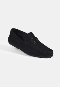 Marineblaue Wildleder Slipper mit runder Zehenform, gesteppten Details und einer dekorativen Schnalle über dem Rist, die eine strukturierte Oberfläche aufweist.