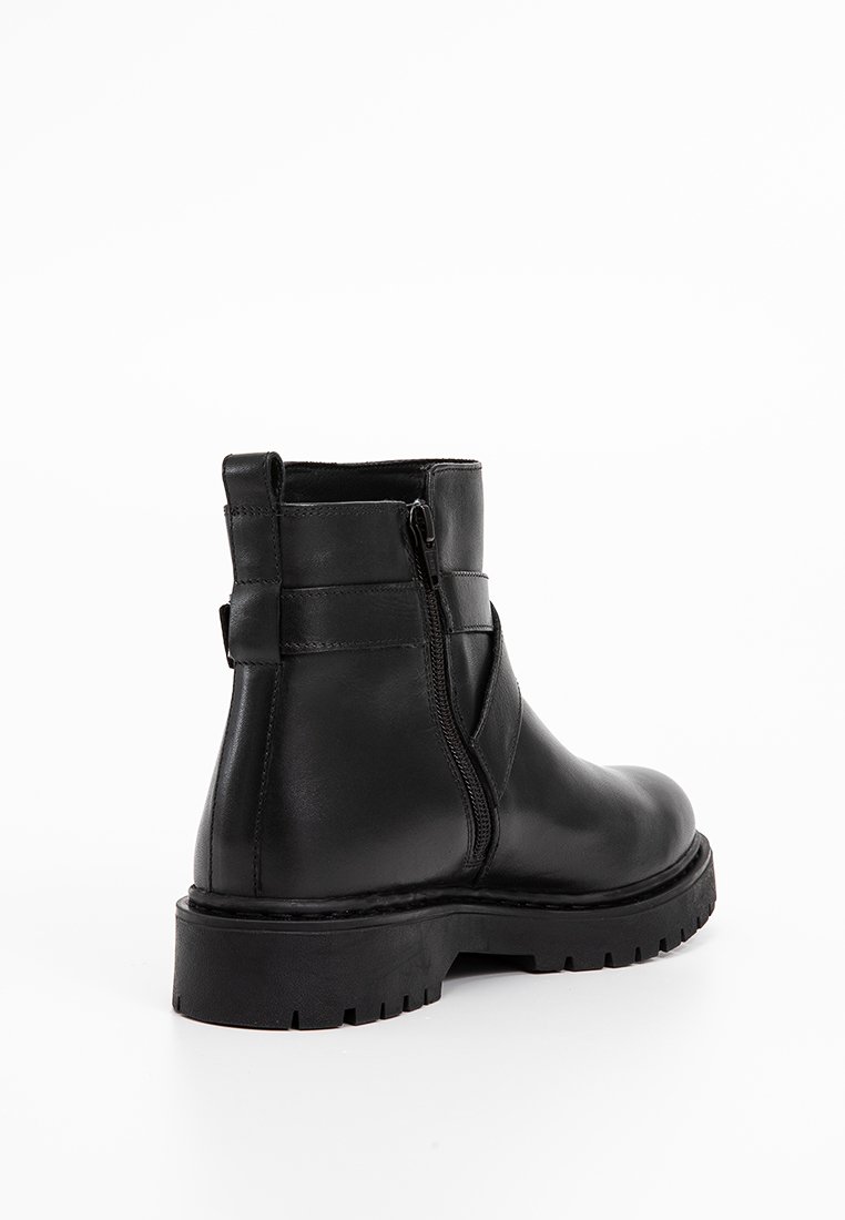 Zwarte leren enkelboot met een zijrits, ronde neus, stevige profielzool en minimale details. Strakke afwerking en stevige constructie.