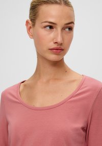 Helles pinkes Langarm-T-Shirt mit einem tiefen Rundhalsausschnitt, aus weichem Stoff gefertigt, mit glatter Textur und einem schlichten Design.