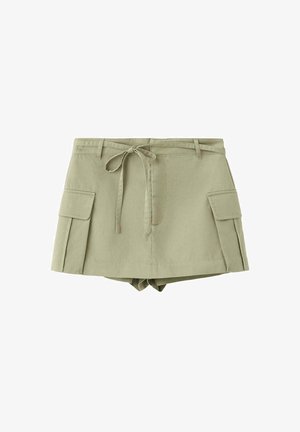 Jupe-short cargo vert kaki avec ceinture nouée à l'avant, deux poches latérales à rabat et shorts sur mesure en dessous.