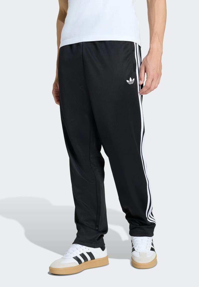 Black athletic pants with white side stripes and a small white logo on the left thigh, made from smooth, lightweight fabric.