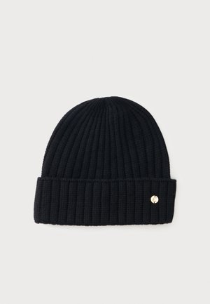 Bonnet en tricot côtelé noir avec revers plié et petit détail logo métallique rond sur un côté, sur fond clair uni.