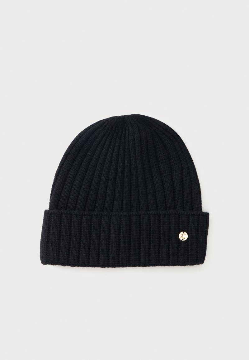 Bonnet en tricot côtelé noir avec revers plié et petit détail logo métallique rond sur un côté, sur fond clair uni.
