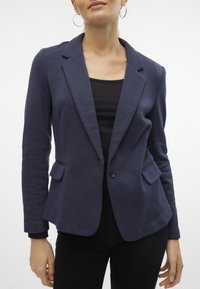 Marineblauer, taillierter Blazer aus strukturiertem Stoff; ausgestattet mit einem Reverskragen, zwei vorderen Taschen und einem Einknopfverschluss.