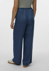 Brede, diepblauwe broek met een elastische tailleband. Gemaakt van een soepele, lichte stof en heeft een strak, minimalistisch ontwerp.