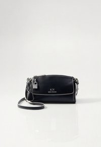 Juoda odinė kūno krepšys su baltu siuvimu, reguliuojama rankena ir mažų užrakto detalė; priekyje išspaustas logotipas.