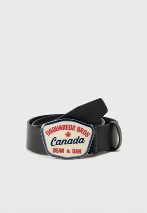 Ceinture en cuir noir avec une large boucle décorative présentant un fond crème, un texte rouge et bleu, et un motif de feuille d'érable.