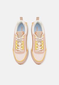 Baskets roses et beiges en mesh et suède, avec des accents blancs et jaunes, lacets plats et une semelle intérieure bleue avec détail du logo.