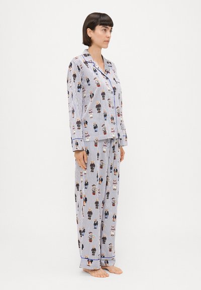 Conjunto de pijama às riscas em algodão com personagens de desenho animado, apresentando uma camisa com botões e calças com cintura elástica. A combinação de cores é branca e azul-marinho.