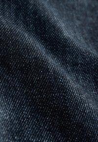 Denim azul oscuro con una textura suave, que presenta un sutil patrón de tejido diagonal y ligeras variaciones de tono para añadir profundidad.