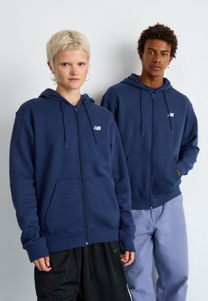 Marineblå zip-up hettegensere laget av bomullsblandingsmateriale, med frontlommer og snorhette, kombinert med uformelle bukser.