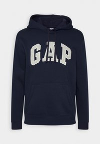 Sudadera azul marino hecha de mezcla de algodón, con un bolsillo frontal y un gran logo de "GAP" en gris claro en el pecho.