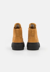 Stivali alla caviglia in pelle tan con suola in gomma nera. Presentano un colletto imbottito, dettagli in cucitura e accenti con logo sul tallone.