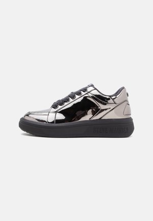 Zapatilla baja con parte superior plateada brillante, cordones negros, suela negra gruesa y logotipo de Steve Madden en el lateral de la suela.