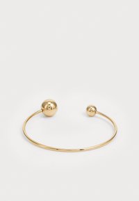 Guldtonad metallarmband med två sfäriska accenter i varje ände. Slät yta och öppen design för justerbar passform.