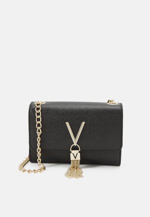 Pochette noire texturée avec bandoulière chaîne dorée, ferrures dorées en forme de V et détail de gland doré sur le rabat avant.