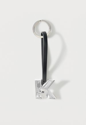 Silver metallic letter "K" keychain with embossed profile and black leather loop attached to a silver ring.