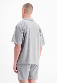 Grijs set met korte mouwen en shorts met een gestructureerd blokpatroon, voorzien van een kraag en een ontspannen pasvorm.