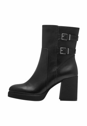 Bottine en cuir noir avec deux accents de boucles en argent, un bout carré et un talon épais empilé. Des panneaux latéraux texturés ajoutent du détail.
