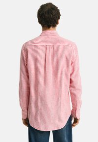 Rood-wit gestreepte lange mouwen shirt met een button-down kraag, afgeronde zoom en een centrale plooi op de rug. Gemaakt van lichtgewicht stof.