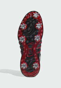 Czarna podeszwa sportowego buta z czerwono-czarnymi rowkami, srebrnymi wkrętami zapewniającymi przyczepność oraz fakturowaną powierzchnią dla lepszego uchwytu.