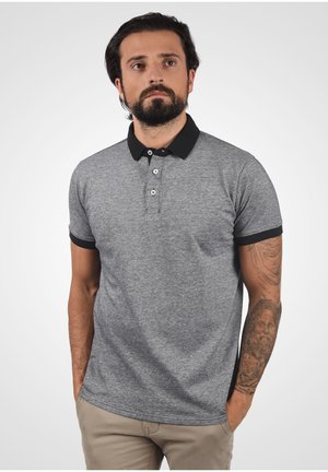 Siva kratka polo majica s crnim ovratnikom, plaketom na tri gumba i kontrastnim crnim manžetama; mekani materijal s suptilnom teksturom.