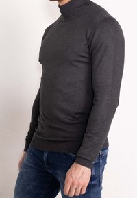 Pull col roulé gris foncé en matière tricotée, à la coupe ajustée, avec des manches longues et un ourlet et col côtelés.