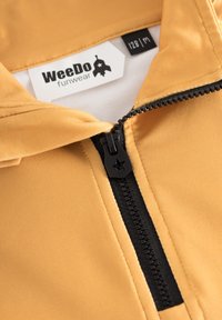 Keltainen vetoketjullinen takki mustalla vetoketjulla, jossa on tähden muotoinen vetonuppi. Tagi lukee "WeeDo funwear," koko 128 m. Silkkinen, synteettinen pinta.